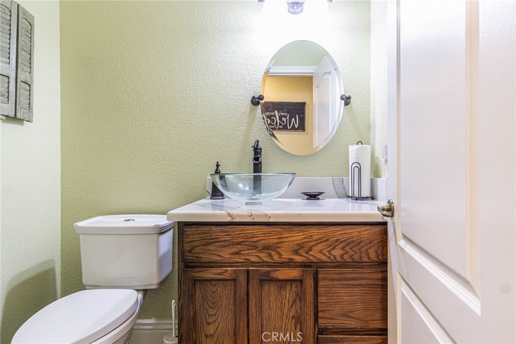 9735 Elsinore Road Oak Hills, CA 92344 - Photo 28 of 64 a bathroom with a toilet sink vanity and mirror
