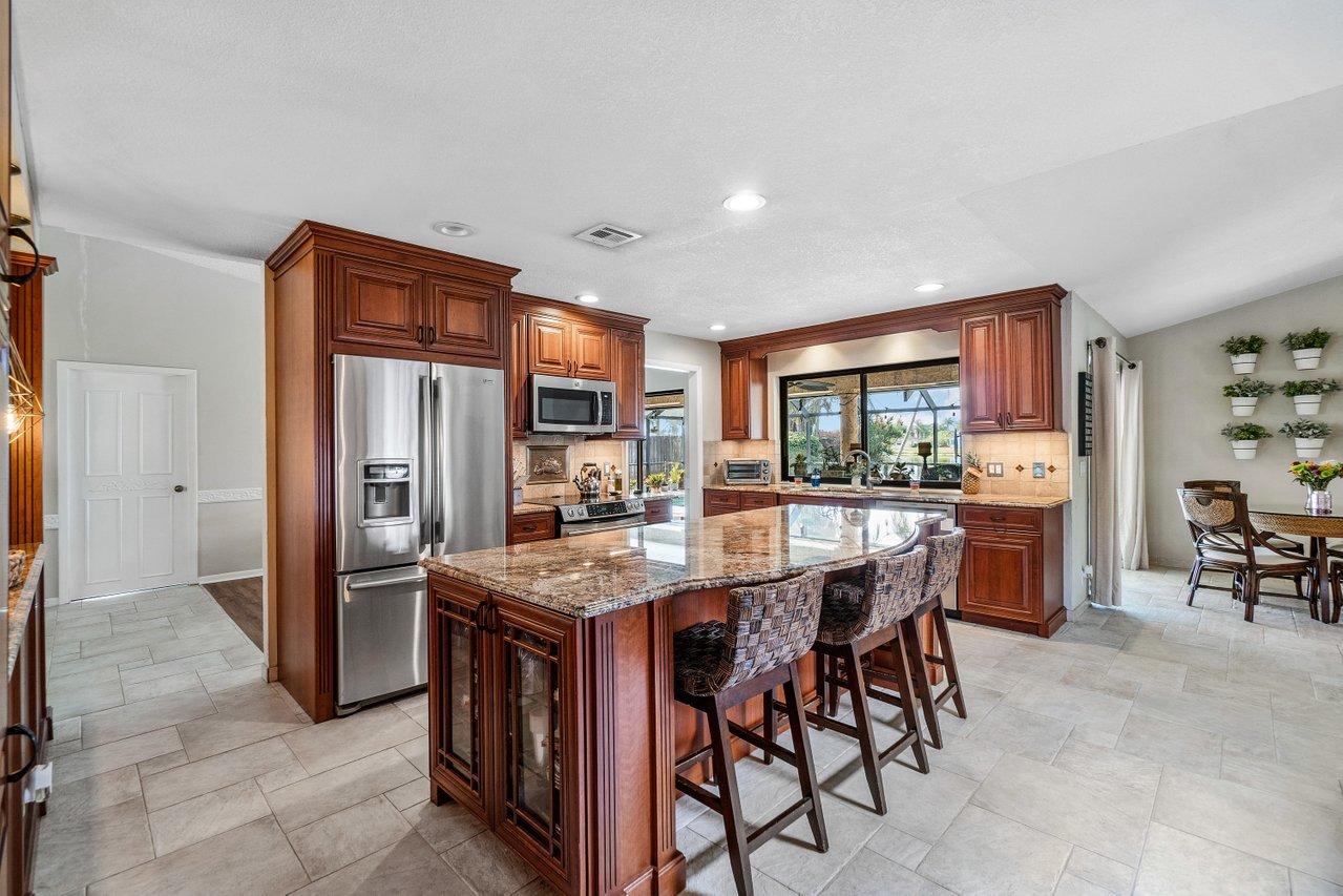 22250 Martella Avenue Boca Raton, FL 33433 - Photo 7 of 45 a kitchen with stainless steel appliances granite countertop a table chairs sink and refrigerator