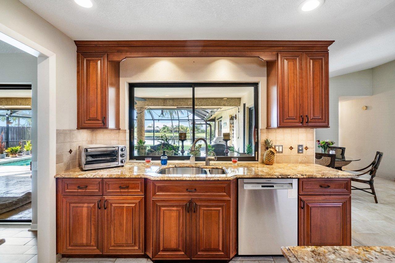 22250 Martella Avenue Boca Raton, FL 33433 - Photo 10 of 45 a kitchen with granite countertop a sink stove and cabinets