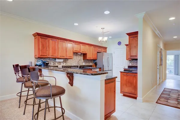 a kitchen with kitchen island granite countertop wooden cabinets and a refrigerator
