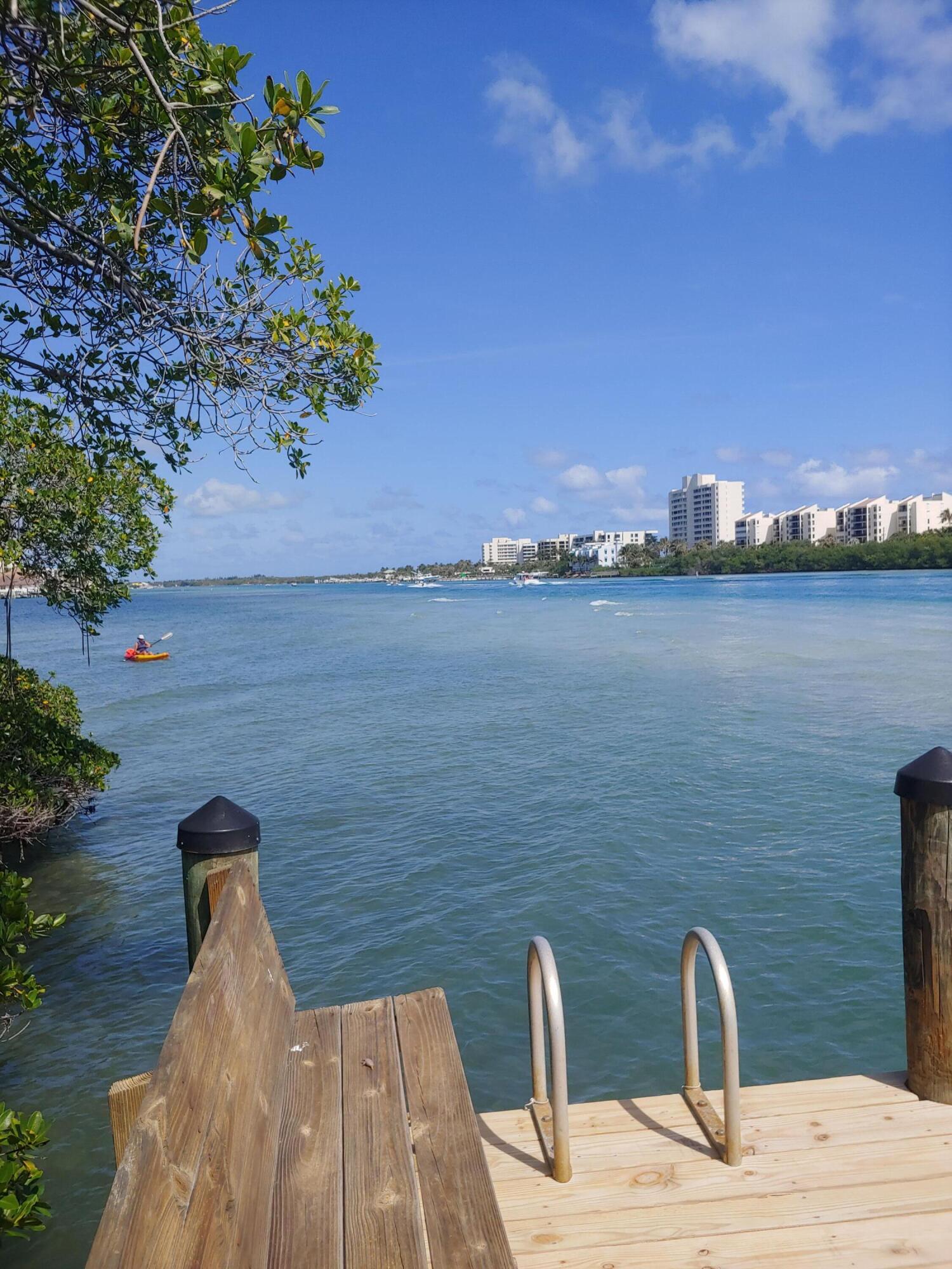 200 Waterway Road, Unit 307 Tequesta, FL 33469 - Photo 7 of 8 a wooden bench sitting on top of a lake