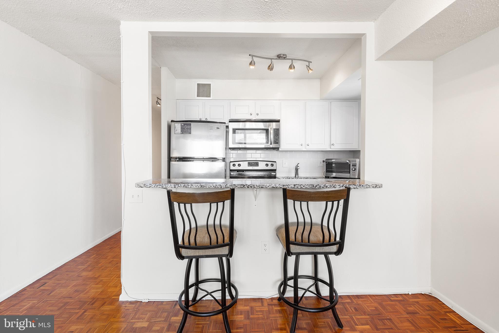 1420 Locust Street, Unit 29J Philadelphia, PA 19102 - Photo 26 of 30 a kitchen with stainless steel appliances granite countertop a table chairs in it and wooden floor