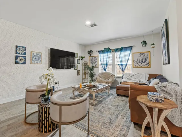 a living room with furniture a flat screen tv and a refrigerator