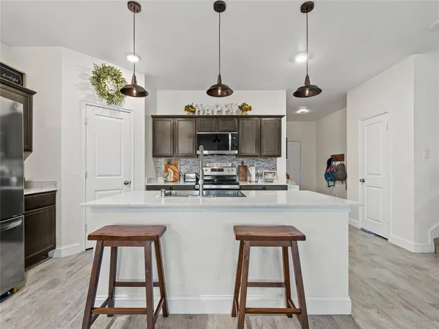 a kitchen with stainless steel appliances granite countertop a kitchen island a stove a table and chairs in it