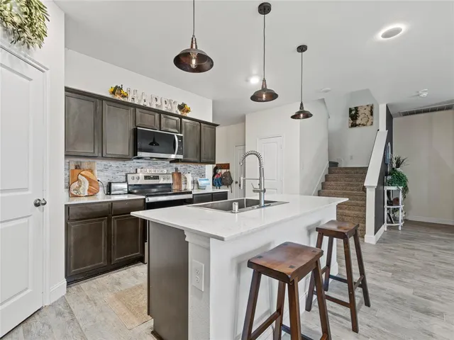 a kitchen with stainless steel appliances kitchen island a table chairs refrigerator and microwave