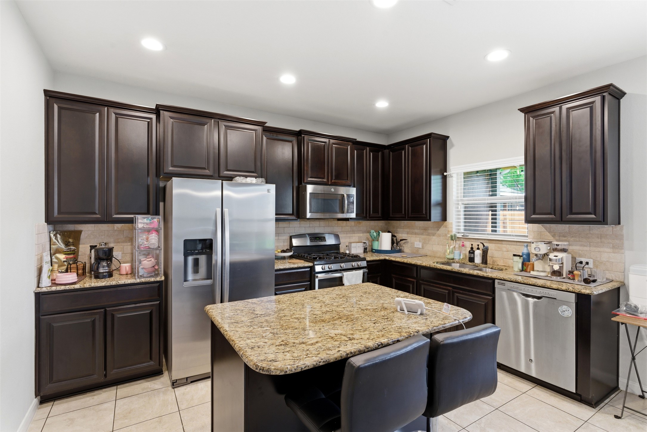 2409 Muzzie Lane Leander, TX 78641 - Photo 11 of 33 a kitchen with kitchen island granite countertop stainless steel appliances a sink stove refrigerator and cabinets