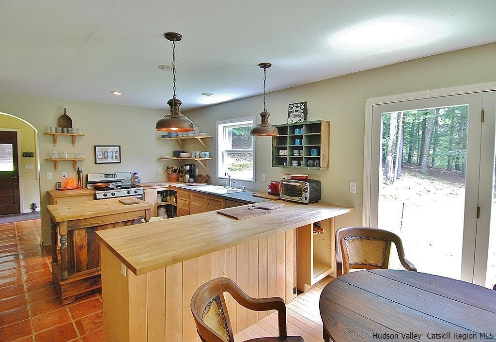 145 Beaverkill Road Kingston, NY 12401 - Photo 6 of 28 a kitchen with stainless steel appliances granite countertop a stove a sink a microwave a dining table and chairs with wooden floor
