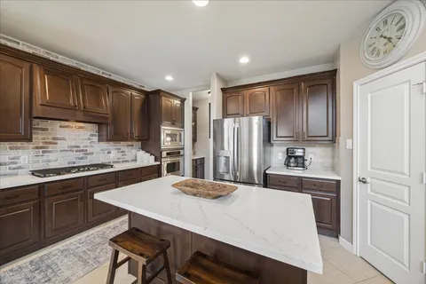 a kitchen with stainless steel appliances granite countertop a sink a stove a refrigerator cabinets and chairs