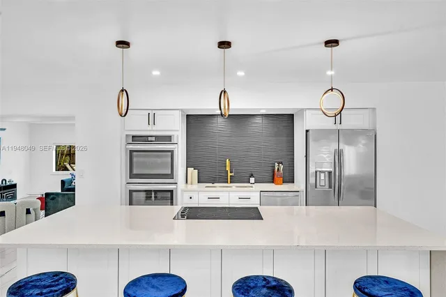 a kitchen with stainless steel appliances kitchen island granite countertop a sink a stove and a refrigerator