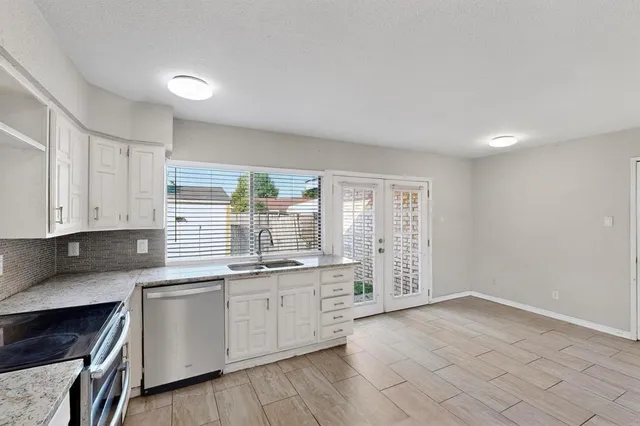 a kitchen with white cabinets stainless steel appliances and window