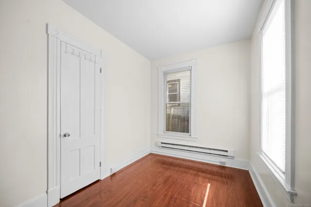 a view of an empty room with a window and wooden floor
