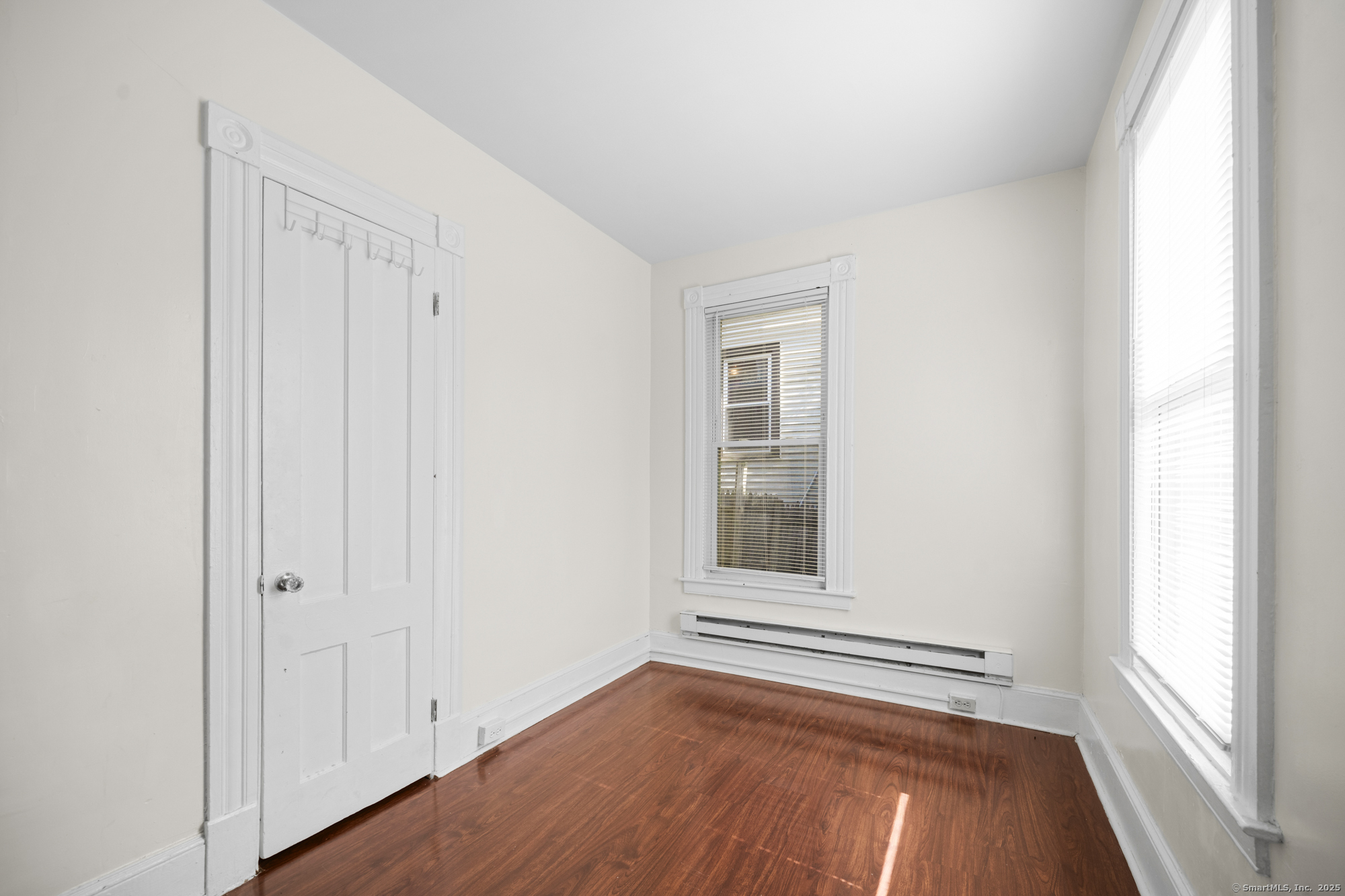 a view of an empty room with a window and wooden floor