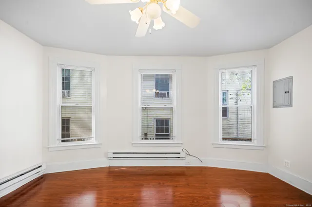 a view of empty room with wooden floor and fan