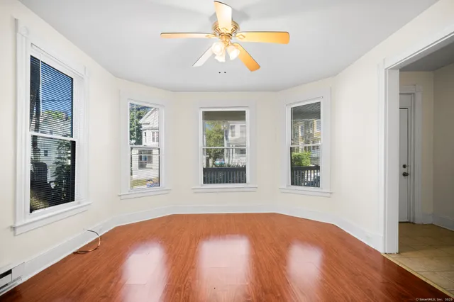 a view of an empty room with window and wooden floor