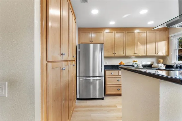 a kitchen with granite countertop a stove a sink and a refrigerator
