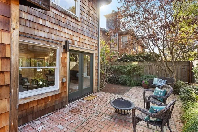 a view of a patio with table and chairs potted plants and large tree