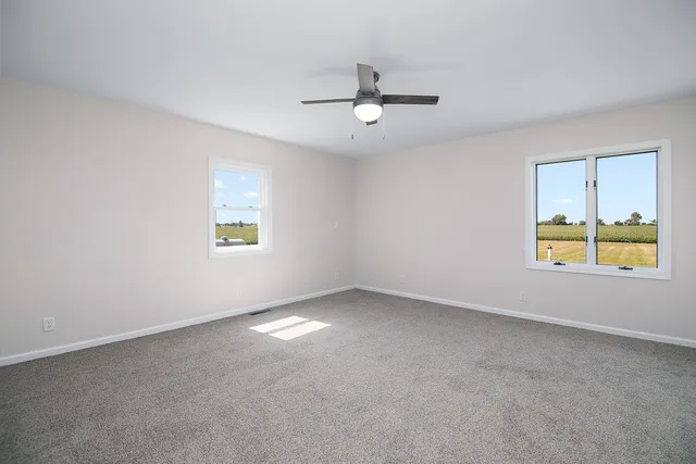 an empty room with a window and a ceiling fan