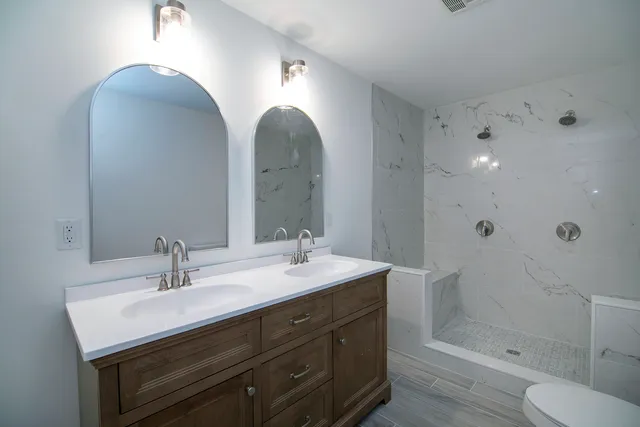 a bathroom with a double vanity sink toilet and shower