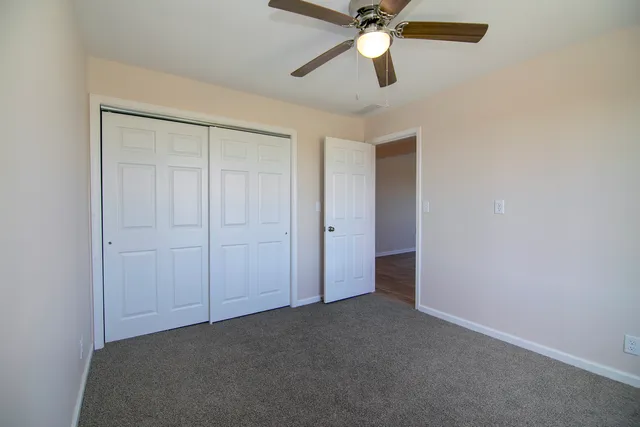 an empty room with closet and a chandelier fan
