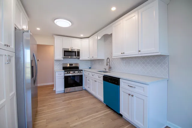 a kitchen with granite countertop white cabinets and stainless steel appliances