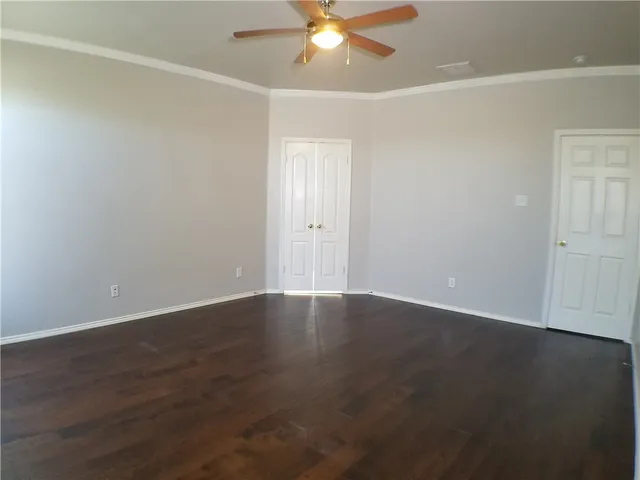 an empty room with wooden floor fan and windows