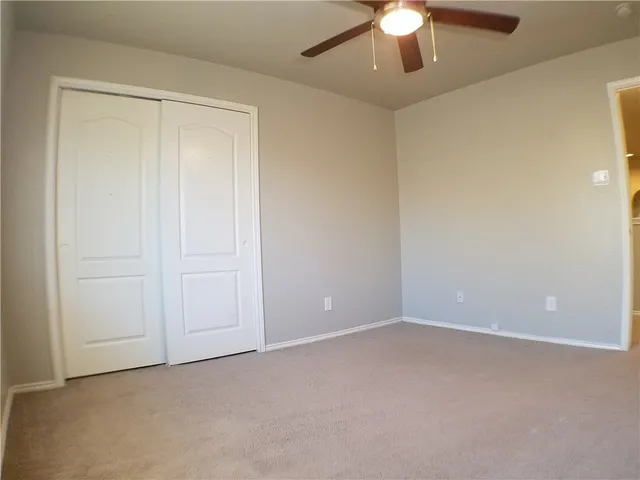 a view of an empty room and chandelier fan