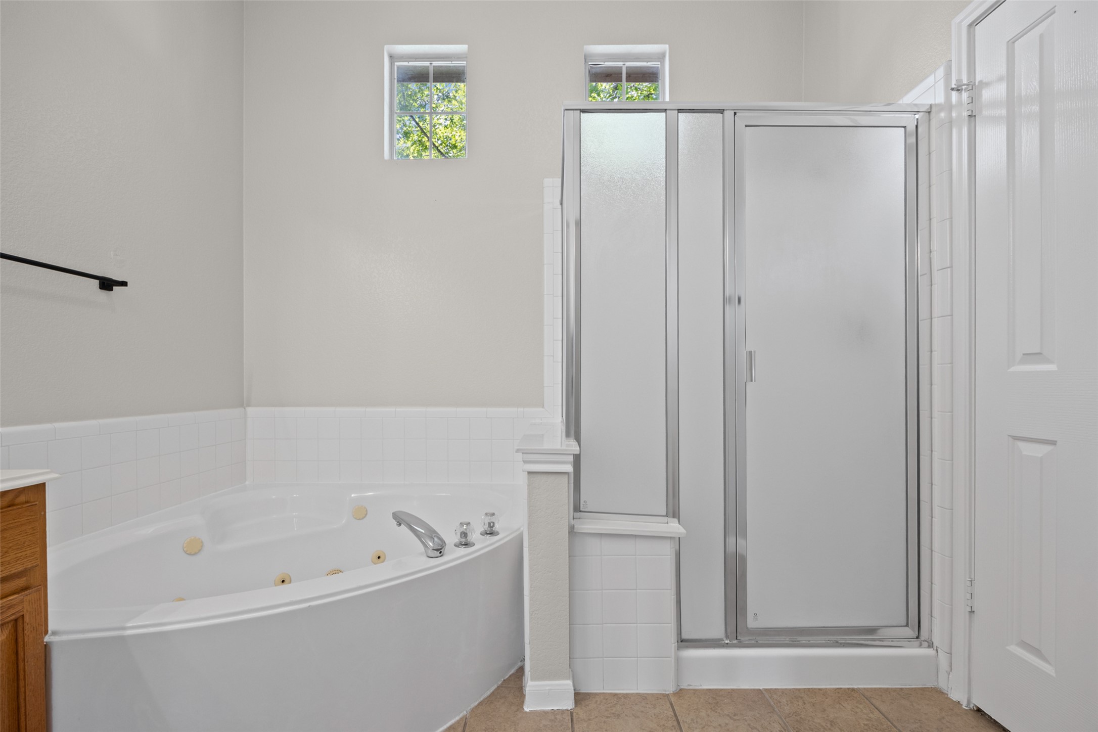 5881 Fergus Kyle, TX 78640 - Photo 21 of 40 High ceilings and neutral tiling frame the soaking tub and glass-enclosed with a separate, standalone shower.