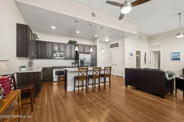 a living room with stainless steel appliances kitchen island granite countertop wooden floor a dining table and chairs