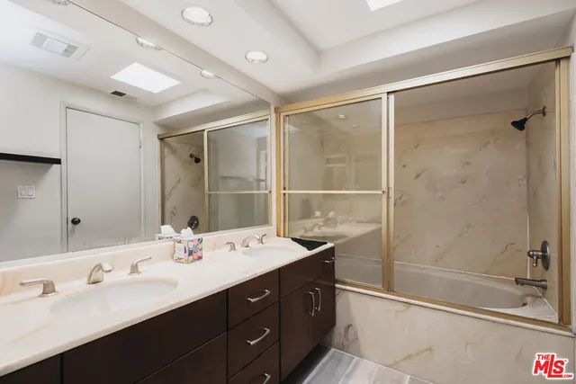 a bathroom with a double vanity sink mirror and shower