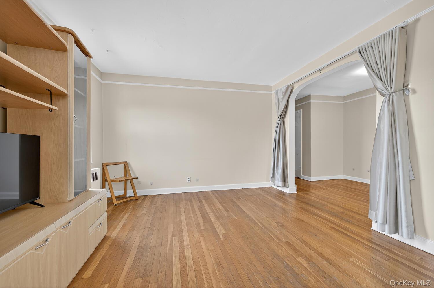 8 Welwyn Road, Unit 3F Great Neck, NY 11021 - Photo 11 of 17 Unfurnished living room featuring light wood-type flooring and arched walkways