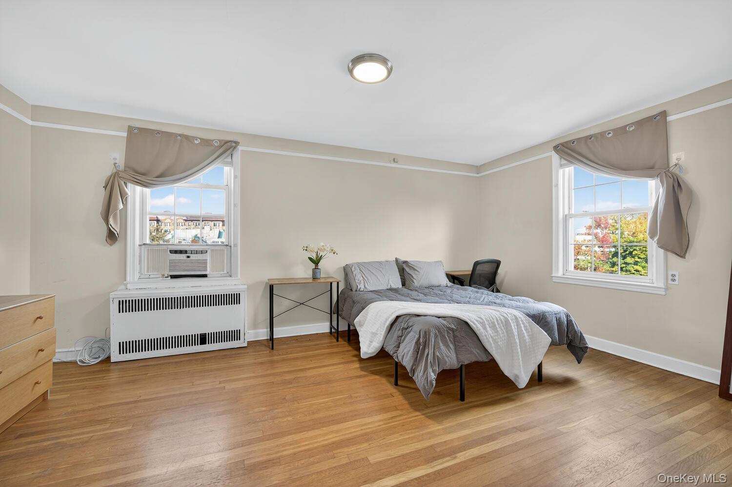 8 Welwyn Road, Unit 3F Great Neck, NY 11021 - Photo 13 of 17 Bedroom featuring radiator heating unit, light wood-style flooring, and cooling unit