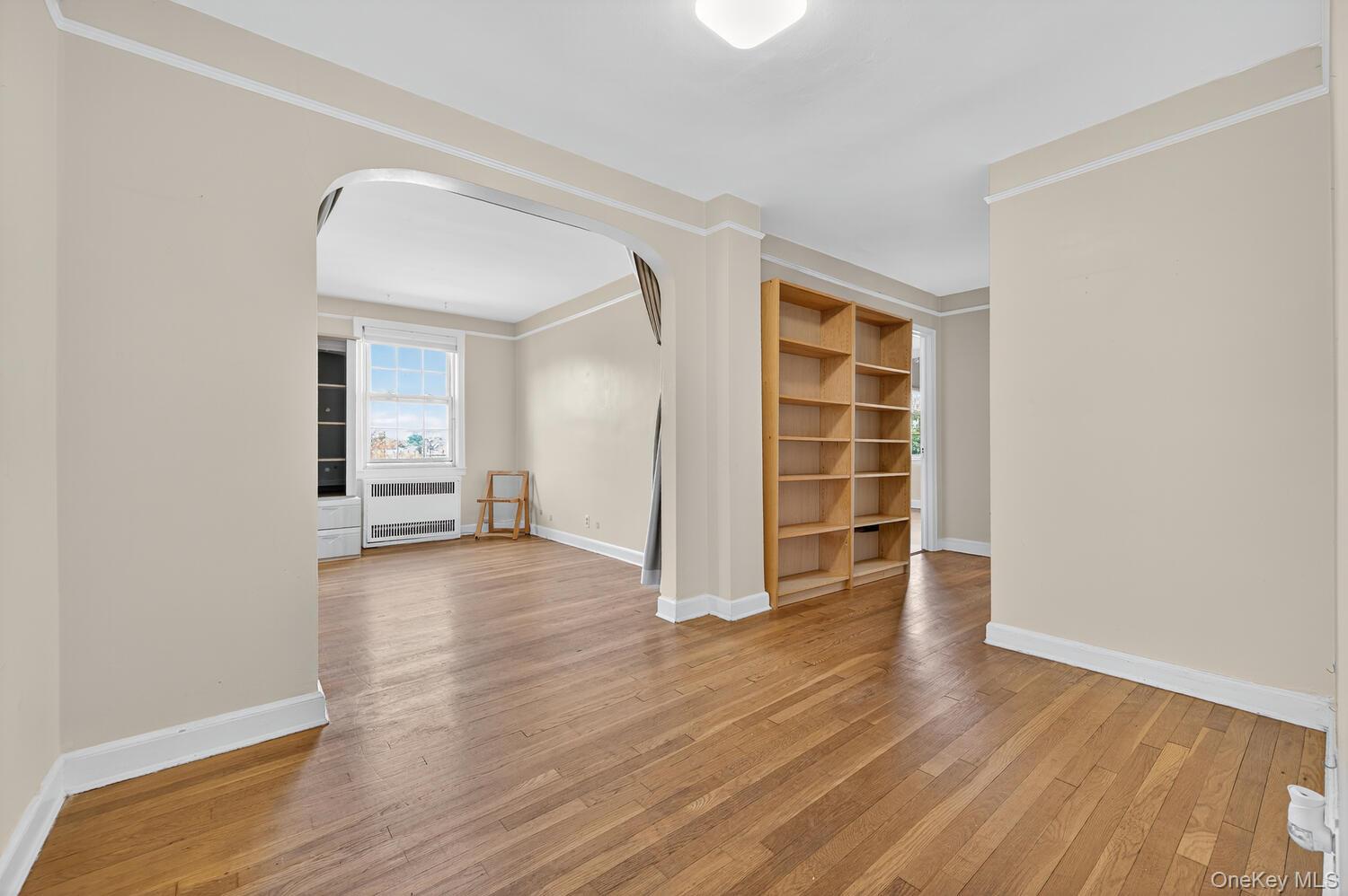 8 Welwyn Road, Unit 3F Great Neck, NY 11021 - Photo 5 of 17 Spare room with arched walkways, light wood-style floors, built in shelves, radiator, and ornamental molding