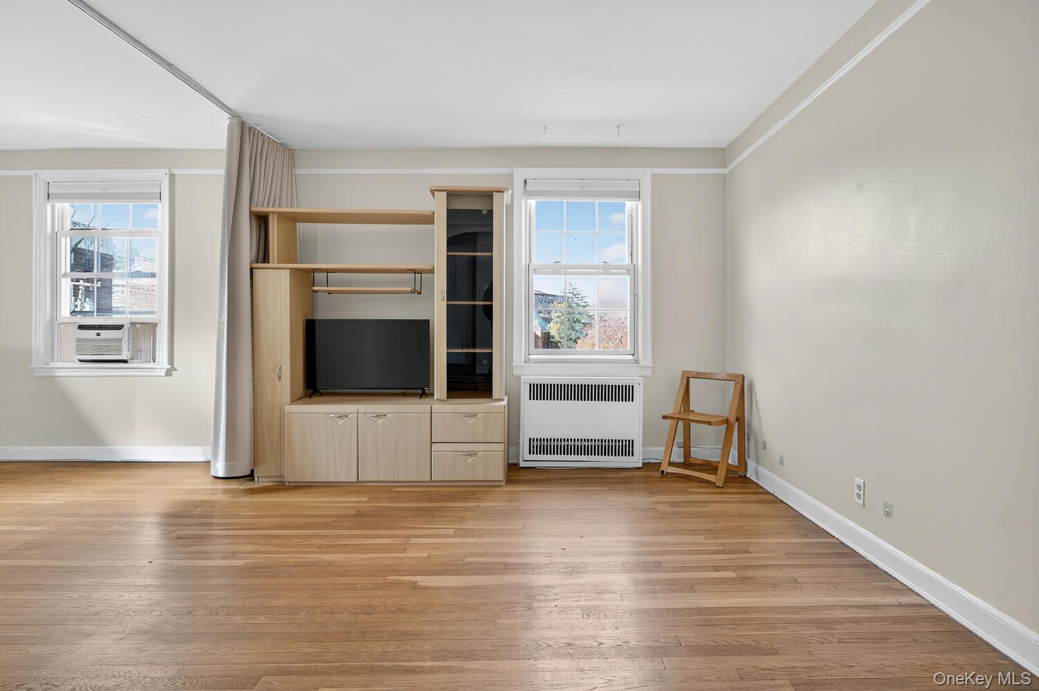 8 Welwyn Road, Unit 3F Great Neck, NY 11021 - Photo 9 of 17 Unfurnished living room with radiator heating unit and light wood-type flooring