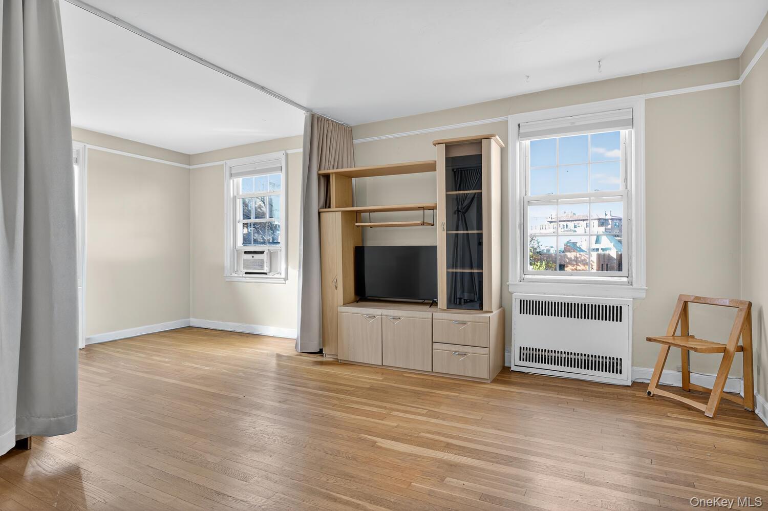 8 Welwyn Road, Unit 3F Great Neck, NY 11021 - Photo 10 of 17 Unfurnished living room featuring radiator heating unit and light wood finished floors