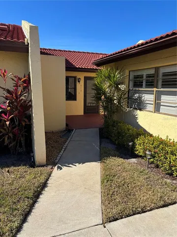 a view of a yellow house with a tree
