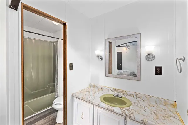 a bathroom with a granite countertop sink toilet and shower