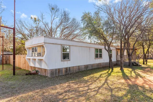a view of a house with a big yard and large tree