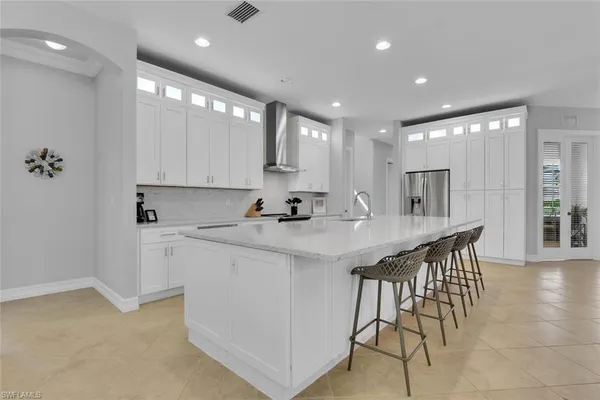 a kitchen with stainless steel appliances granite countertop a sink a stove a refrigerator and island with wooden floor