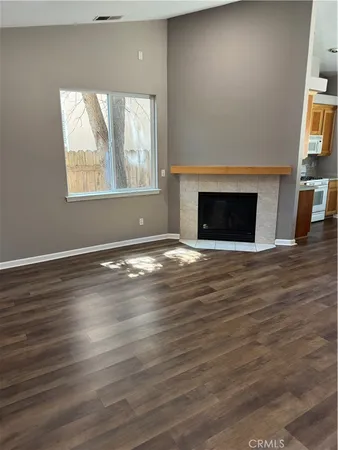 an empty room with wooden floor a fireplace and windows