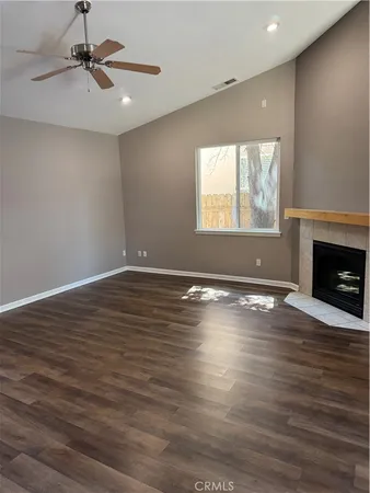 an empty room with wooden floor fireplace and windows
