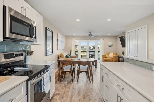 a kitchen with stainless steel appliances granite countertop a stove top oven a sink dishwasher a dining table and chairs with wooden floor