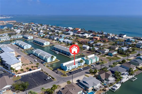 an aerial view of a city with lots of residential buildings ocean and mountain view in back