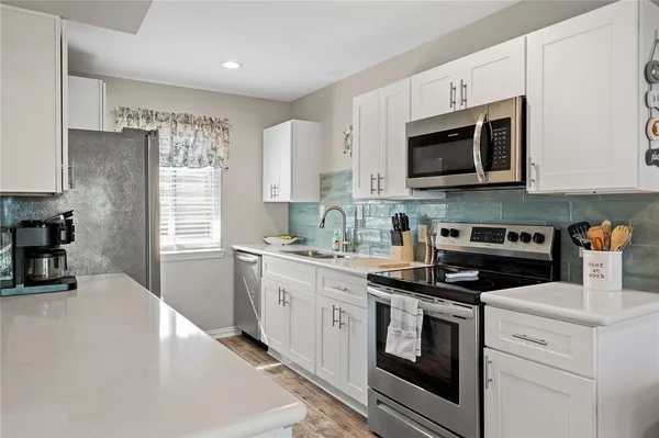 a kitchen with stainless steel appliances granite countertop grey cabinets a stove a sink and a microwave