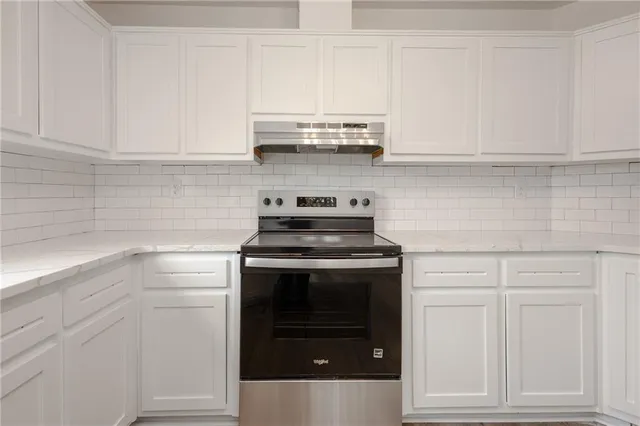 a kitchen with white cabinets and appliances