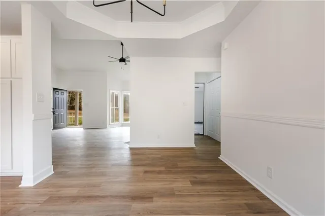 a view of an empty room with wooden floor and a ceiling fan