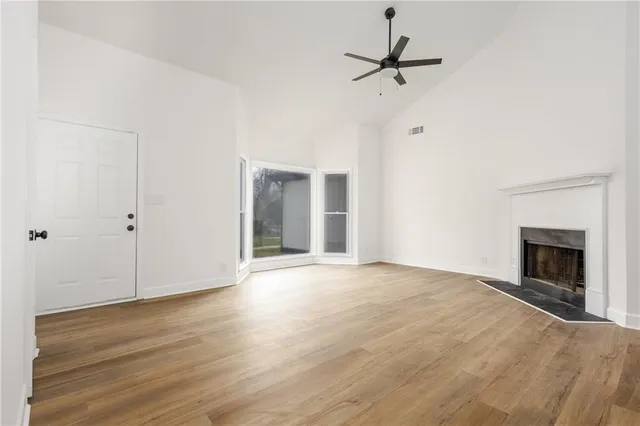 a view of an empty room with a ceiling fan and wooden floor