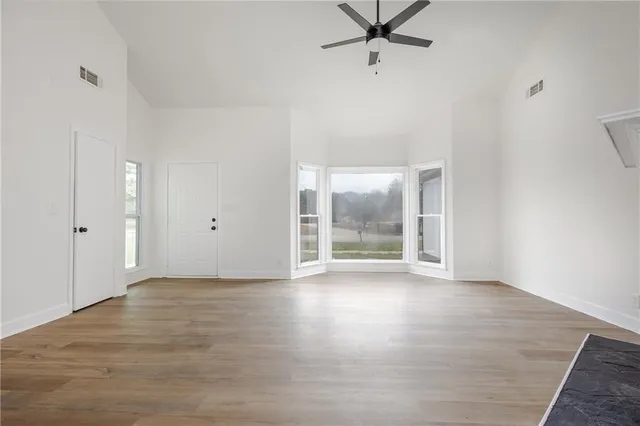 an empty room with wooden floor and windows