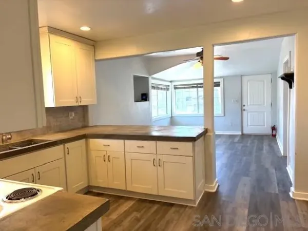 a kitchen with granite countertop a sink cabinets and wooden floor