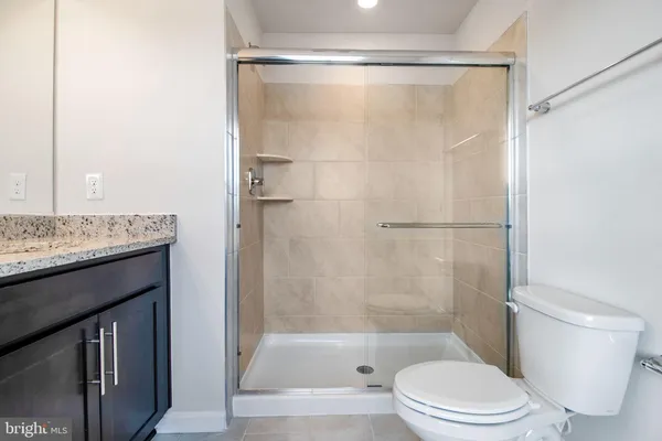 a bathroom with a granite countertop bathtub shower and a toilet