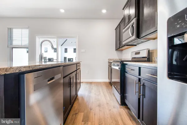 a kitchen with stainless steel appliances granite countertop a refrigerator a stove and a sink with wooden floor